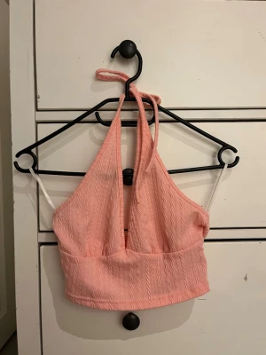 Rosa och vit halterneck topp från SHEIN - Två snygga halterneck toppar från SHEIN i storlek XS, en i ljusrosa och en i vit. Båda har vågigt strukturmönster, knyt i nacken och croppad passform. Perfekta till sommaren och lätta att matcha med jeans eller kjol.