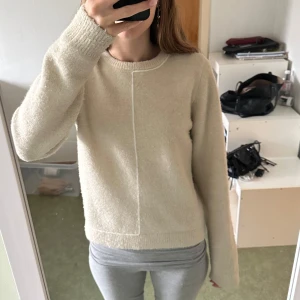Beige stickad tröja från Zara - Mysig beige stickad tröja från Zara med lång ärm och rund hals. Tröjan har en unik sömdetalj framtill. Den är nopprig som man ser på bilden. Tröjan är märkt M men jag skulle säga att den är mer mot S (beror på hur man vill ha passformen)