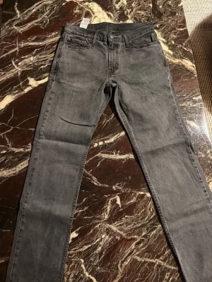Grå Levi's 511 jeans - Säljer ett par grå Levi's 511 jeans med klassisk femficksdesign och smal passform. Jeansen har en snygg tvättad look, normal midja och raka ben. I mycket bra skick