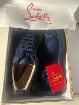 Christian Louboutin Spikes Suede Sneakers – Marinblå - Säljer ett par Christian Louboutin sneakers i marinblå mocka med de ikoniska spikes-detaljerna. Skorna är i mycket fint skick och kommer med originalkartong, dustbags och äkthetskort. Den klassiska röda Louboutin-sulan är ren och knappt använd.   Perfekta för dig som söker lyxiga, exklusiva sneakers med riktigt premiumkänsla. Tillverkade i Italien – kvalitet rakt igenom.  Detaljer: 	•	Märke: Christian Louboutin 	•	Modell: Spiked Suede Sneakers 	•	Färg: Marinblå 	•	Material: Mocka 	•	Storlek:43