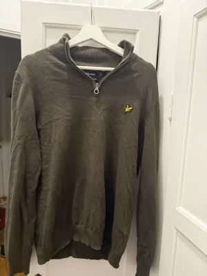 Mörkgrön half zip tröja från Lyle & Scott - Säljer en mörkgrön långärmad tröja från Lyle & Scott med ribbad krage och half zip-dragkedja. Tröjan har den klassiska gula loggan broderad på bröstet och är tillverkad i mjuk bomull. Perfekt för dig som gillar stilren och enkel design. Inte använd många gånger och sitter fint på personer med L i storlek. 