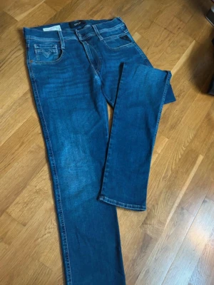 Replay Anbass Hyperflex jeans blå - Säljer ett par blå Replay Anbass Hyperflex jeans med klassisk femficksdesign och snygga kontrastsömmar. Jeansen har normal passform och är tillverkade i stretchigt jeansmaterial för extra komfort. Perfekta för dig som gillar stilrena och bekväma jeans.