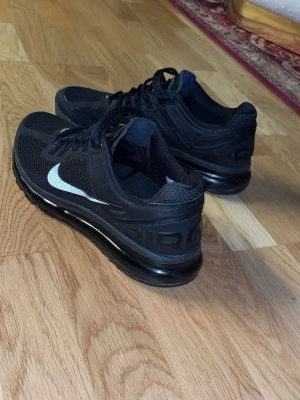 Nike Air Max svarta sneakers - Säljer ett par svarta Nike Air Max sneakers med vit swoosh på sidan och AIR-text bak på hälen. Skorna har en synlig luftbubbla i sulan, mesh- och syntetmaterial samt snörning. Perfekta för dig som gillar sportig och clean stil. Väldigt sällan används tagit väl hand om dom st 42 snabb affär 599 skick 8/10