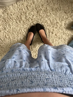 Blommig ljusblå kjol från Gina Tricot - Supersöt ljusblå kortkjol från Gina Tricot med små blommor i blått. Kjolen har smock i midjan, volangdetaljer och är gjord i ett lätt och luftigt material. Perfekt för varma dagar och ger en fräsch vibe till din outfit.