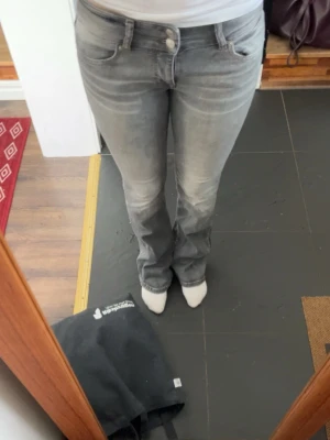 Grå bootcut jeans - Säljer ett par grå jeans från bershka med bootcut och lowaist.