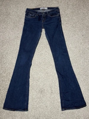 Vintage lågmidjade bootcut jeans från Hollister - Snygga mörkblå bootcut jeans från Hollister med klassisk femficksdesign och kontrastsömmar. Säljer då jag köpte fel storlek💖W24 innerbenslängd 84 cm