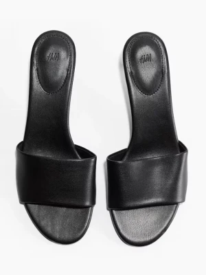 Svarta sandaler med låg klack från H&M - Stilrena svarta sandaler från H&M med öppen tå och bred rem över foten. Skorna har låg klack och en minimalistisk design i slätt syntetmaterial som ger en clean och modern vibe. Perfekta till jeans eller kjol för en enkel men snygg look.