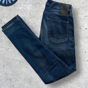 Replay anbass jeans - Säljer ett par Replay Anbass jeans i mörkblå tvätt med snygga slitningar. Modellen är slimfit. Klassiska femficksjeans med läderpatch bak i midjan och diskreta kontrastsömmar. Perfekta till sneakers och t-shirt.
