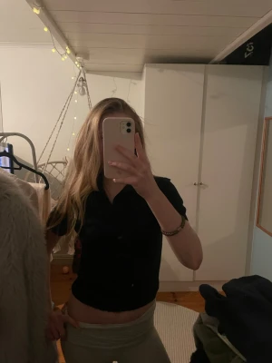 Svart croppad polotopp från H&M - En svart croppad polotopp från H&M med korta ärmar och klassisk krage. Toppen är stickad och har en enkel, stilren design som passar perfekt till jeans eller kjol. Mjuk och skön att bära, perfekt för dig som gillar en clean look.