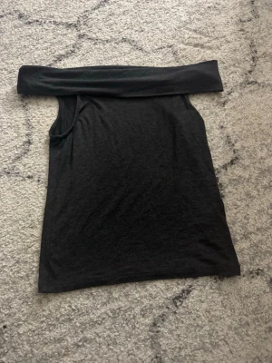 Svart offshoulder topp Kappahl - Säljer en svart offshoulder topp från Kappahl i storlek 170. Toppen är ärmlös och har en bred kant upptill som sitter snyggt över axlarna. Perfekt till sommarens outfits och enkel att matcha med olika stilar. Aldrig använd och mycket bra skick.