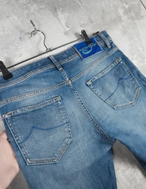 Blå jeans från Jacob Cohën (prisförslag) - Snygga blå jeans från Jacob Cohën med klassisk femficksdesign och blå patch bak i midjan. Jeansen har en rak passform med något smalare ben, diskreta slitningar och ljusare partier framtill. Tillverkade i mjukt denimtyg med snygga kontrastsömmar på bakfickorna.