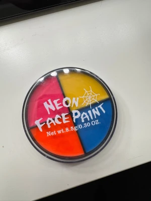 Neon ansiktsfärg palett - Säljer en rund palett med neon ansiktsfärg i fyra färger: rosa, gul, orange och blå. Perfekt för kreativa sminkningar och festivaler. Kommer i en plastförpackning med genomskinligt lock och cool spindelnätsdetalj på framsidan. Innehåller 8,5 g färg.