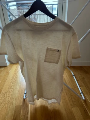  t-shirt Clean Cut Copenhagen - Säljer en stilren vit t-shirt från Clean Cut Copenhagen . T-shirten har korta ärmar, rund halsringning och en liten bröstficka med diskret X-detalj. Perfekt basic-plagg i mjuk bomull.