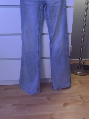 Bootcut jeans från Cheap Monday storlek 25 - Säljer ett par ljusblå bootcut jeans från Cheap Monday med coola gröna detaljer och logga bak. Jeansen har klassisk femficksdesign och är tillverkade i jeansmaterial. Perfekta för dig som gillar retrovibbar och vill sticka ut lite extra.störlok 25