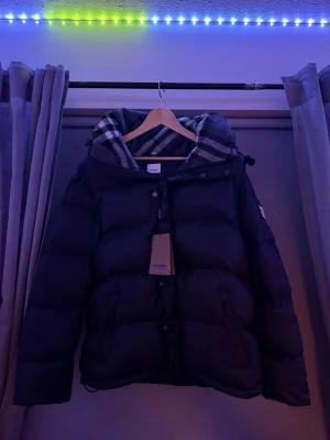 Burberry puffer  - Säljer min burberry jacka då den inte passar mig väldigt fint skick ja har aldrig använt den förutom när ja prövade den, du kan även göra den till en väst genom att ta bort armarna då de finns dragkedjor gömda inne i jackan, storleken är xxl men passar xl då burberry har rått små storlekar, skriv gärna om ni har frågor elr nått liknande mvh