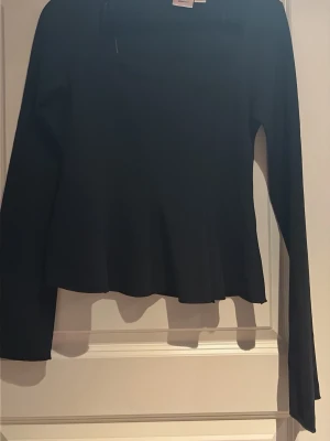 Svart långärmad topp från Gina Tricot - En stilren svart långärmad topp från Gina Tricot. Toppen har en enkel och klassisk design med raka linjer, vilket gör den lätt att matcha med olika outfits. Perfekt basplagg i garderoben. Den är aldrig använd