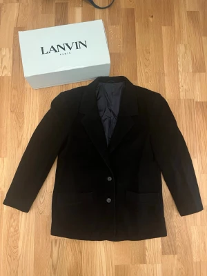 Svart kavaj i kashmir och ull - Säljer en svart kavaj från Cashmere and wool i en lyxig mix av kashmir och ull. Kavajen har klassisk passform med två knappar framtill, fickor och helfodrad insida. Perfekt för dig som vill ha en stilren och tidlös look.