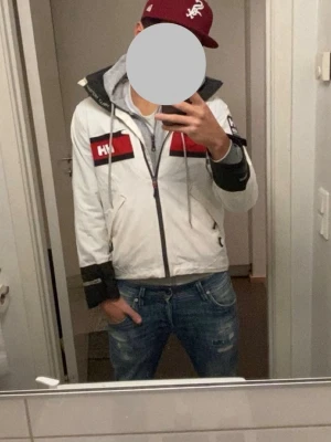 Helly Hansen jacka - Vit Helly Hansen seglings jacka med röd luva. Fick av min mamma och säljer pga att den är för liten för mig. Storlek: S Skick: 8/10