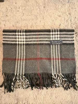 Burberrys halsduk - Säljer nu en mörkgrå burberrys halsduk i Vädligt bra skick! Endast använd ett fåtal gånger. Hör av er vid frågor eller mer information! Pris går att diskutera!
