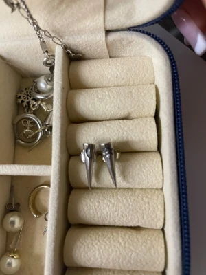 Silvriga örhängen med måne och sol - Säljer ett par coola silvriga örhängen med spetsig form. Ena örhänget har en ingraverad måne och det andra en sol, vilket ger en unik vibe. Perfekta för dig som gillar detaljer och vill sticka ut lite extra.