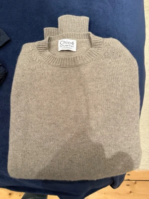 Beige stickad tröja från Chloé Schuterman - Säljer en beige stickad tröja från Chloé Schuterman by Nathalie Schuterman, 70% ull och 30% kashmir. Tröjan har samma passform som hennes gamla klassiska tröjor med olika städer på. Går ej att köpa längre. Storlek är one size men passar allt från S-L beroende på hur man vill att den ska sitta. Nypris 3400