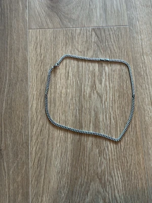 Två silverfärgade kedjor - Säljer två stilrena kedjor i silverfärg. Ena kedjan är tunn och diskret medan den andra är bredare med chunky länkar. Perfekta att bära tillsammans för en trendig lager-på-lager-look eller var för sig för olika vibes. 100kr för den tunna 200 för den större