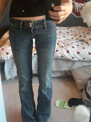 Blå bootcut jeans med låg midja - Säljer ett par blå jeans med bootcut och låg midja. Jeansen har dubbla knappar i linningen och klassiska bakfickor. Däremot har jag lagt ner jeansen, (se sista bilderna) 