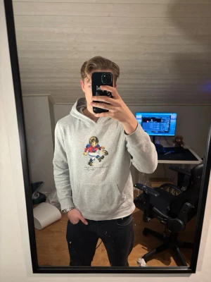 Grå polo bear hoodie  - Säljer en grå polo bear hoodie från Ralph lauren då den inte används så mycket. Den är stilig och passar till allt. Den passar som storlek S. Den har en liten fläck på framsidan men som inte märks av. (Visas på sista bild) Skickar paket inom 1 dag. Bara att hör av sig vid minsta lilla fundering.