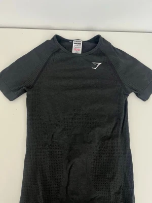 Gymshark tränings t-shirt - Svart tajt tränings T-shirt från gymshark. Knappt använd eftersom den inte passa och köpte den i london så kunde inte lämna tillbaka 