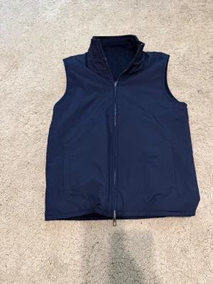 Mörkblå reversible väst från  Loro Piana  - Säljer en marinblå reversible väst från Loro Piana i tekniskt microfiber/nylon med fleece-insida. Lätt och bekväm. Helt oanvänd. Nypris cirka 2300euro. Inga kvitton kvar. Välkomnar seriösa prisförslag.