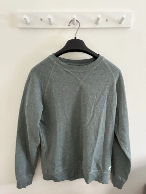 Grön sweatshirt  - En stilren grön sweatshirt från lager 157 med rund halsringning och diskret logga nertill. Tröjan har långa ärmar och klassiska ribbade muddar vid ärmslut och nederkant. Perfekt för en chill och avslappnad look.