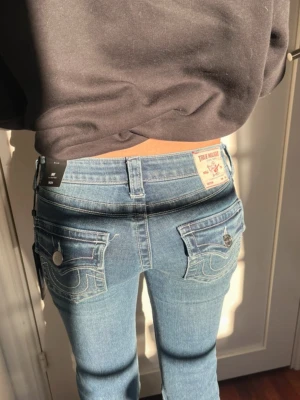 True Religion Joey Low-Rise Flare Jeans - Säljer ett par blå True Religion Joey jeans med låg midja och flare-ben. Helt nya, oanvända men lapp kvar. Hon på bilden är 165 cm
