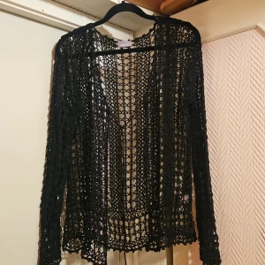 Svart virkad kofta från South - Svart långärmad kofta från South i virkad design. Koftan är öppen framtill och har ett luftigt, genombrutet mönster. Tillverkad i 100% viskos, perfekt att slänga över en topp för en chill look.