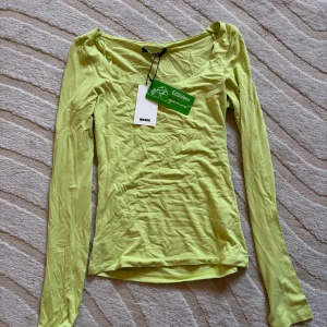 Grön långärmad topp från Bik Bok - Helt ny långärmad topp från Bik Bok med rundad halsringning. Tunn och mjuk i materialet, perfekt för lager-på-lager eller som den är. Tillverkad i EcoVero viskosblandning för en hållbar vibe. Enkel och stilren design som är lätt att matcha.