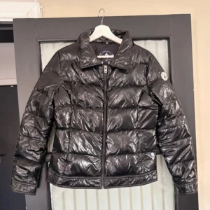 Svart dunjacka från JOTT - Snygg svart pufferjacka från JOTT med glansig finish och avtagbar krage. Superfint skick, storlek M.🌸