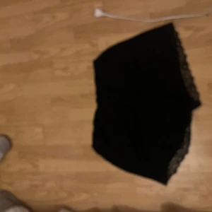 Svarta spetskantade shorts från H&M - Säljer ett par svarta shorts från H&M i storlek L. De har en mjuk och bekväm passform med snygga spetsdetaljer längs kanterna som ger en extra touch. Perfekta för dig som gillar stilrena och enkla plagg med lite edge.