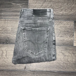 Jack & Jones jeans  - Snygga grå skinny jeans från Jack & Jones, modell Skinny Liam. Jeansen har klassisk femficksdesign, smal passform och är tillverkade i stretchigt jeanstyg för extra komfort. Perfekta för dig som gillar en tight och modern look. Midja. 38cm längd 100cm. Ifall det inte finns någon bild i annonsen där jag bär plaggen jag säljer så är det för att jag ej kan ha storleken heller passformen, så kolla måtten för storlek och googla på modellnamnet för passform 😉