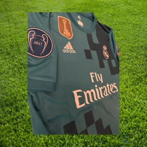 Ronaldo - UCL 2018 - Nyskick/helt oanvänd Cristiano Ronaldo Real Madrid bortatröja från 2018. Det var med denna tröja Ronaldo gjorde cykelsparken mot Juventus i Champions League ö. Tröjan har till och med UCL trycken på ärmarna. Tveka inte att höra av er för fler frågor och bilder!