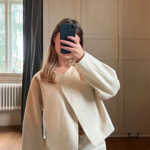 Off-white omlottkofta  - Säljer en superfin omlottkofta med långa ärmar och snyggt fall. Koftan/jackan har en stilren och modern look med lite boxig passform. Materialet känns mjukt och lite tjockare.