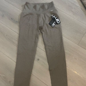 Bruna ribbade leggings från Aim'n - Helt nya med prislapp! Snygga bruna leggings från Aim'n med ribbad struktur och hög midja. De är stretchiga och sitter tight, perfekta för träning eller chill. Färgen är en djup brun och materialet är mjukt och följsamt. Aim'n-logga i metall på linningen ger en extra detalj.