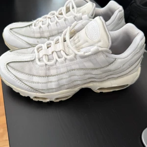 Nike Air Max 95 vita sneakers - Nike Air Max 95 sneakers i helvitt med klassiska vågiga paneler och synlig Air-dämpning i sulan. Väldigt bekväma. Skorna är rena. Originalpris: 2399kr
