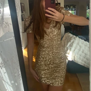 Guldig klänning - Säljer denna fina klänning perfekt till nyår eller fest storlek S och super fint skick. Klänningen är lite avklippt för att bli kortare se bild 5 för att se det slitna utav det men inget man speciellt tänker på
