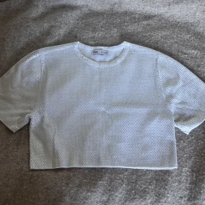 Vit glittrig topp från Zara - Superfin vit topp från Zara med croppad passform. Paljetterna sitter fast hårt, ingen risk för att de åker av! Använd en gång, passar bra med linne under! Toppen skulle passa vem som helst egentligen oberoende storlek. Nypris 400