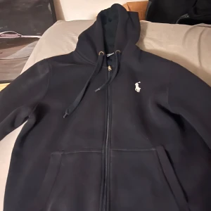 Svart hoodie från Polo Ralph Lauren (ÄKTA) - Fått som present men passar ej bra väljer att sälja den en helt ny är 2200kr men lägger ut den för 1500 eftersom jag använt den i 2 veckor men den är då helt ny inga konstigheter. Passar M - L
