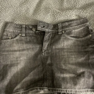 Svart/grå lågmidjade jeanskjol  - Snygg svart jeanskjol från Zoul i storlek 36. Ser ut som nya och säljs inte längre, kort snygg och är inne nu! Skriv privat om ni vill ha bild på 🥰 