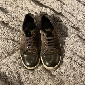 Bruna sneakers från Lanvin i mocka - Säljer ett par bruna sneakers från Lanvin med ovandel i mocka och lackad tå. Skorna har bruna snören, vit sula och rund tå. Snygg kontrast mellan material och en stilren design som passar till många outfits. Jag har köpt nya snören till de för de andra försvann och det finns såklart små skavanker med skorna därav priset, kan även sänka vid snabb affär🤗🤗