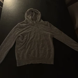 Grå kashmirhoodie från Sayless - Mjuk och lyxig grå hoodie från Sayless i 100% kashmir. Tröjan har huva med snörning, långa ärmar och ribbade muddar. Perfekt för dig som vill ha en stilren och bekväm look med exklusiv känsla. PRIS KAN DISKUTERAS😀