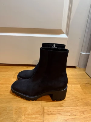 Boots från Zara - Snygga svarta mockaboots från Zara i mjuk mocka med en låg klack. Modellen har rund tå och dragkedja på sidan för enkel på- och avtagning. Perfekt för dig som gillar stilrena och trendiga skor med lite edge. Nypris: 499kr