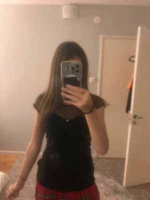 Svart prickig blus med mesh-detalj - Säljer en söt blus med mesh upptill och prickigt mönster. Använd ett fåtal gånger.