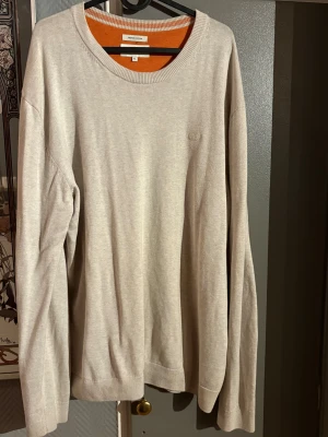 Beige bomullströja Tom Tailor - Snygg beige långärmad tröja från Tom Tailor i premium bomull. Tröjan har rund halsringning, diskret broderad logga på bröstet och ribbade muddar vid ärmslut och nederkant. Perfekt för dig som gillar enkel och stilren design.